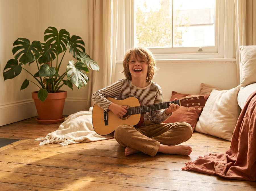 Kind spielt lachend eine kleine Gitarre